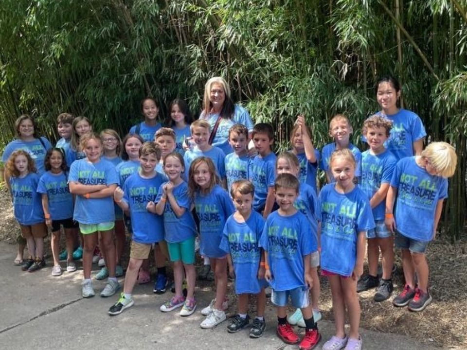 Treasure Camp kids in matching blue T-shirts posing outdoors